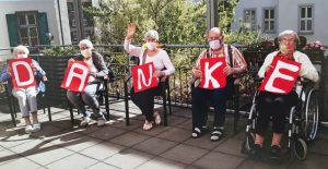 Bewohnerinnen und Bewohner des Seniorenzentrums halten Schilder mit den Worten DANKE hoch.