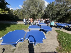 Ein Gruppenfoto der Schülerinnen und Schüler mit blauen Tischtennisplatten im Vordergrund.